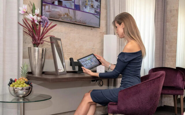 Frau am Schreibtisch mit In-Room Tablet mit digitaler Gästemappe better.guest im Hotel Merkur Baden-Baden