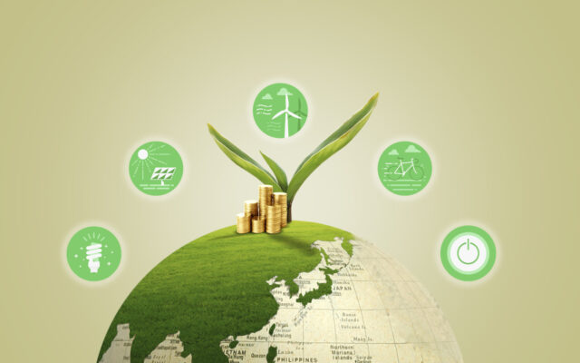 Grüne Erdkugel auf der Münzen und eine junge Pflanze liegen, sowie Symbole von erneuerbaren Energien
