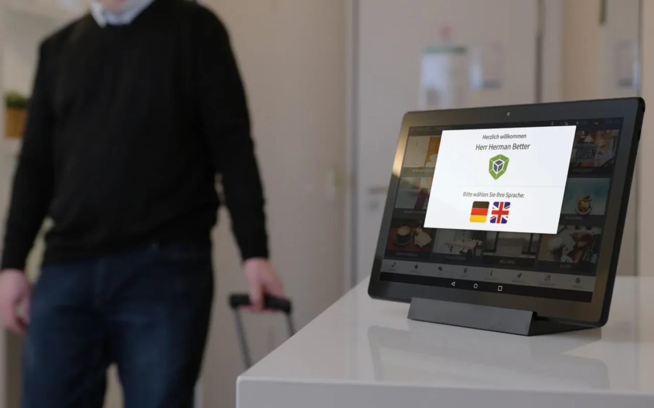Gast betritt Hotelzimmer und die digitale Gästemappe auf dem Tablet zeigt personalisierte Willkommensnachricht an