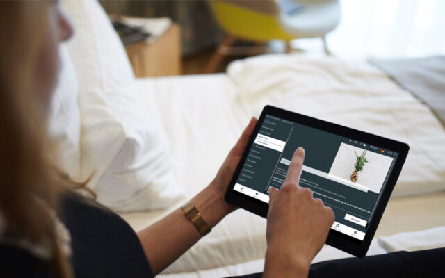 Frau im Hotelzimmer bestellt tägliche Zimmerreinigung über die Green Option auf dem In-Room Tablet mit digitaler Gästemappe better.guest ab