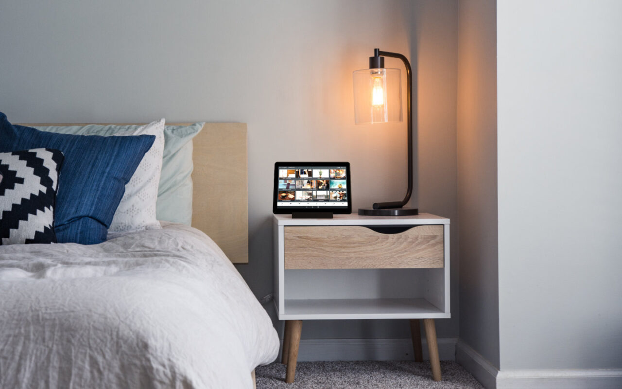 Hotel room with bed and bedside table on which the digital guest directory is placed on the tablet
