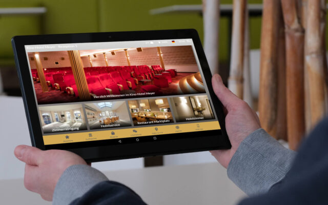 Gast hält Tablet mit digitaler Gästemappe better.guest Kino-Hotel Meyer