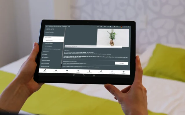 Gast hält In-Room Tablet mit digitaler Gästemappe auf der die Green Option abgebildet ist