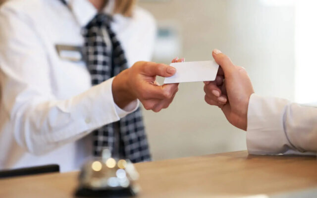 Hotelmitarbeiterin an der Rezeption übergibt einem Gast die Schlüsselkarte