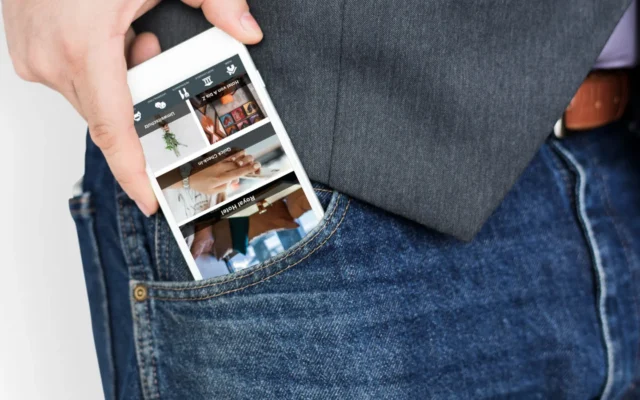 mann hält smartphone mit hotel app fest und steckt es in hosentasche