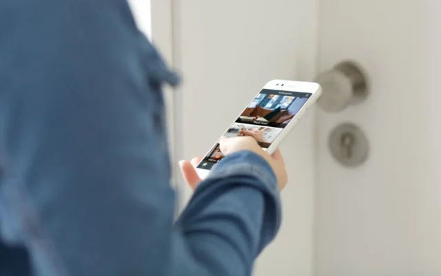 Hotelgast hält smartphone in der hand vor hotelzimme rtü mit hotel app