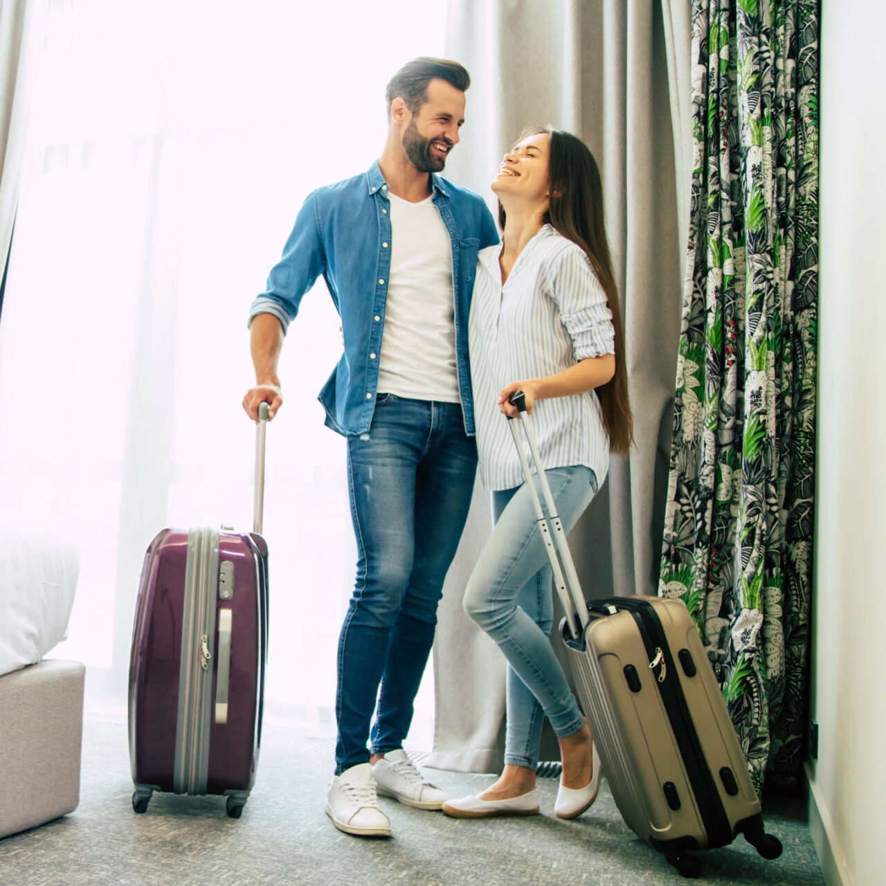 Zwei glückliche Hotelgäste mit ihren Koffern im Hotelzimmer