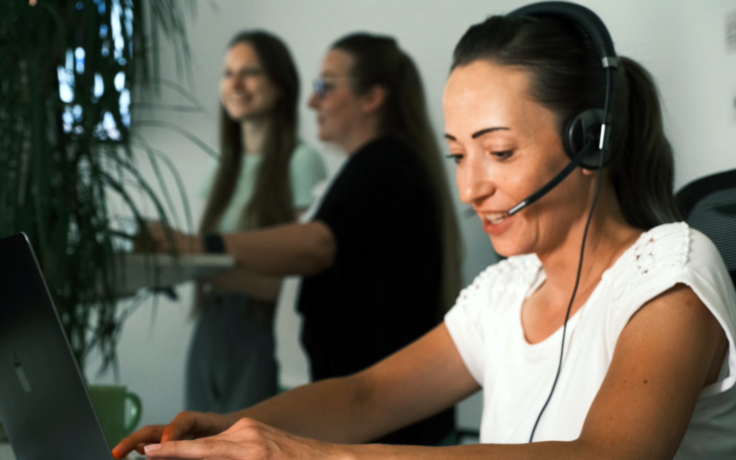 betterspace support mitarbeiter beantworten am schreibtisch e-mails während ein anerder mit headset telefoniert