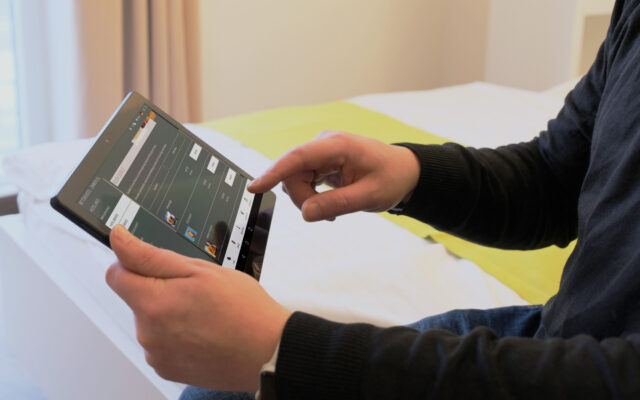 Mann bestellt Roomservice über digitale Gästemappe auf dem In-Room Tablet im Hotelzimmer