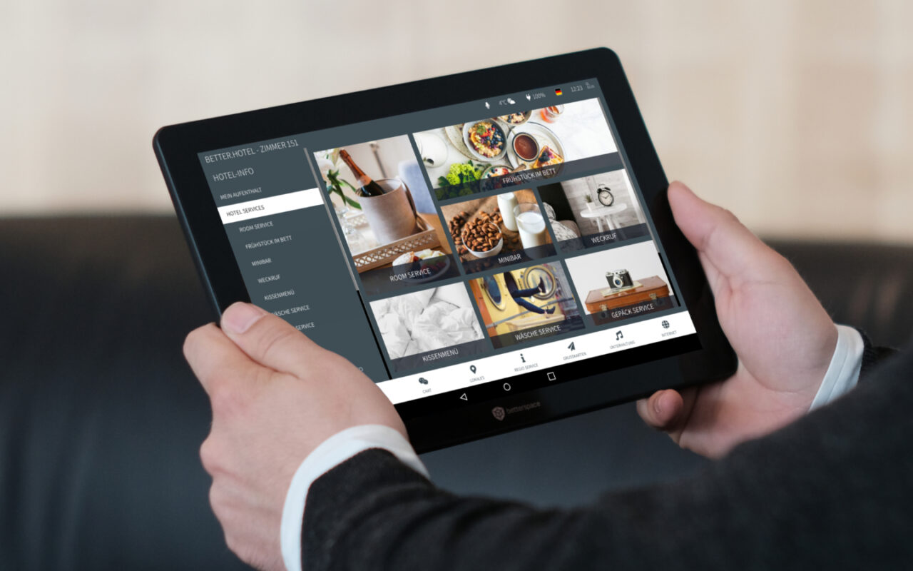 Mann mit digitaler Gästemappe auf dem In-Room Tablet im Hotelzimmer sieht sich Hotel-Services an Zimmerservice Roomservice Angebote