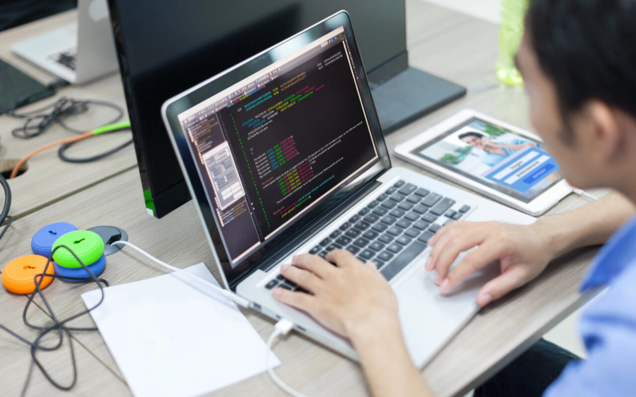 Software-Entwickler sitzt am Laptop und programmiert