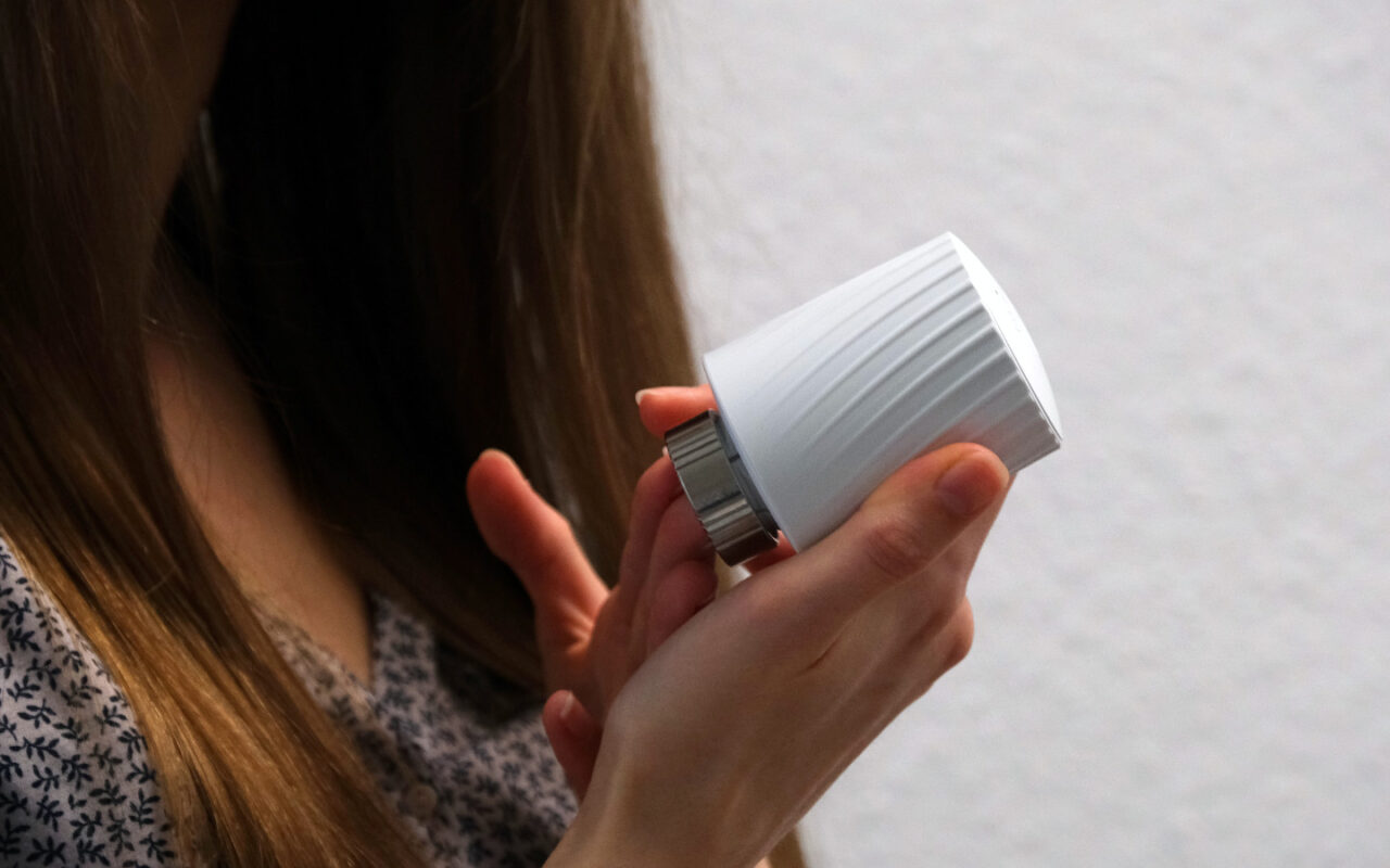 Frau hält intelligentes Heizkörperthermostat MClimate