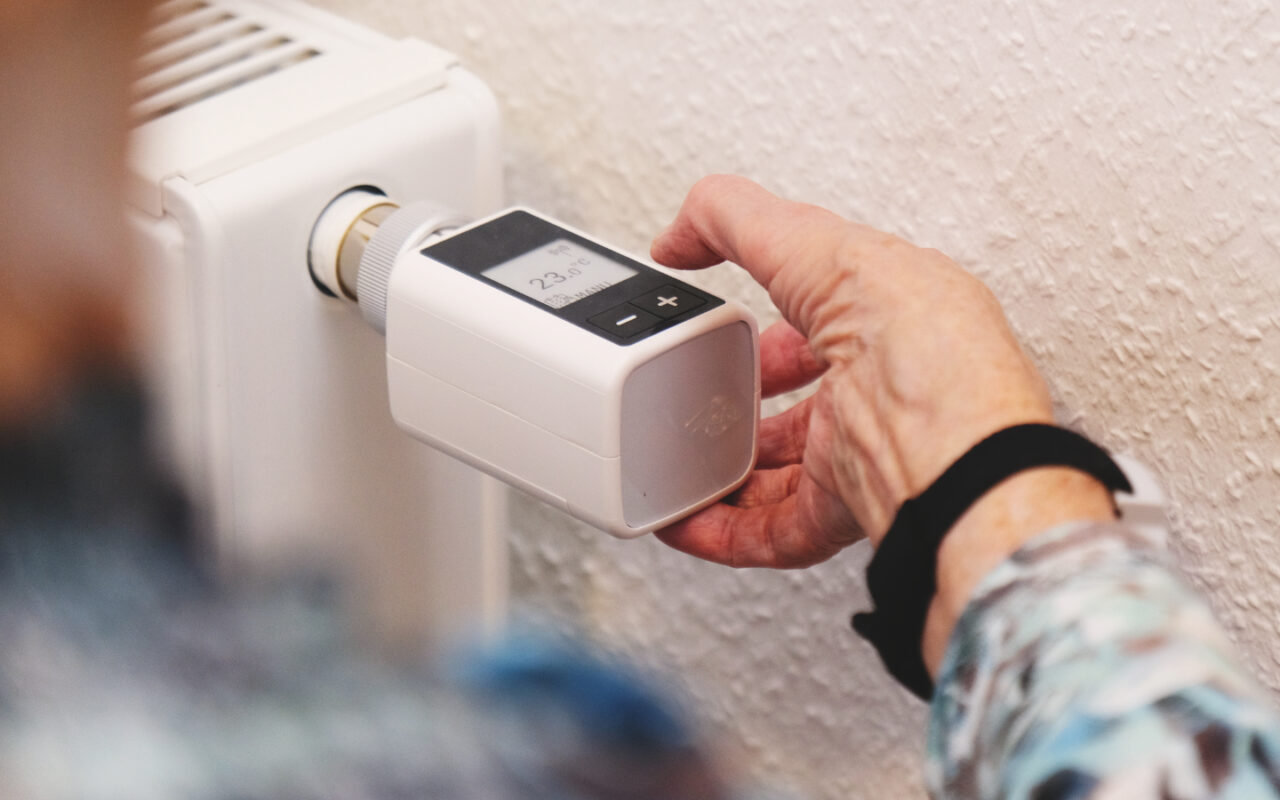 Ältere Frau stellt Temperatur am Heizkörperthermostat von dnt ein